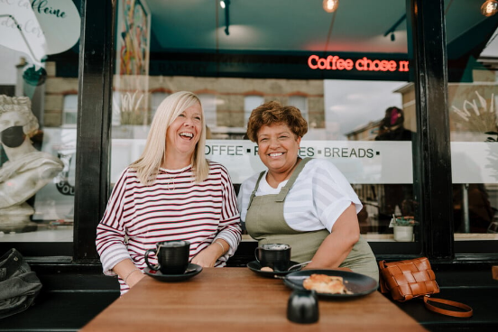 two people sat outside a cafe smiling and laughing